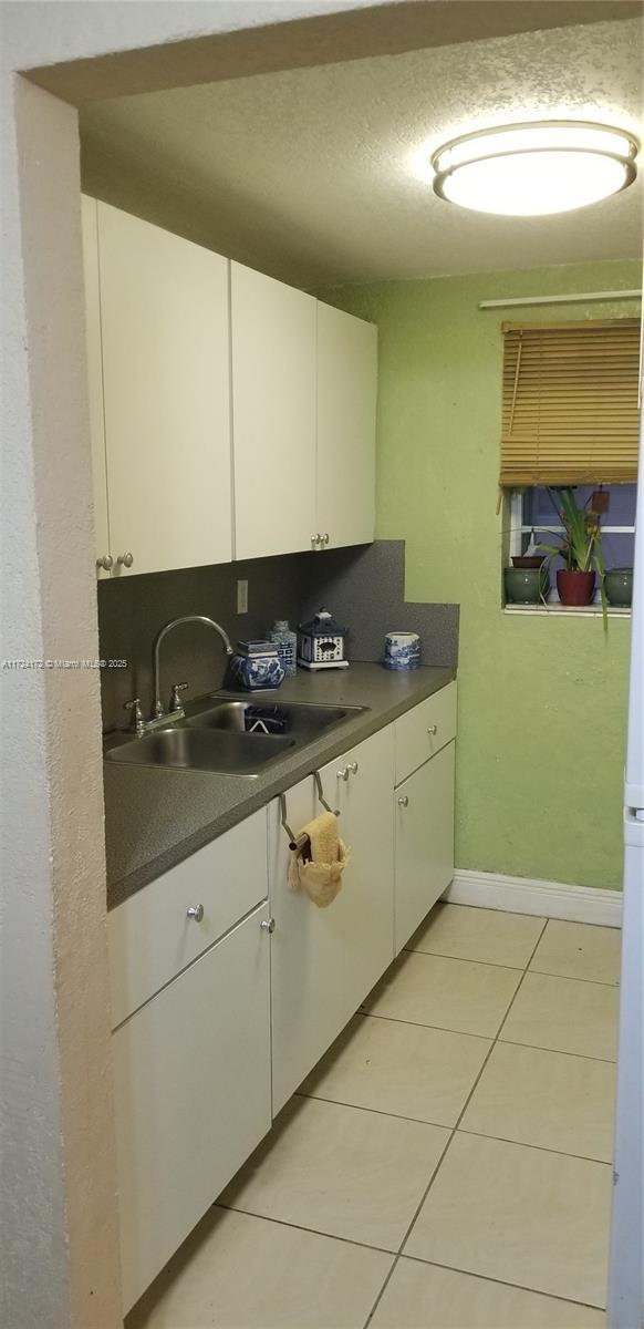 kitchen featuring sink, white cabinetry, light tile patterned floors, and tasteful backsplash