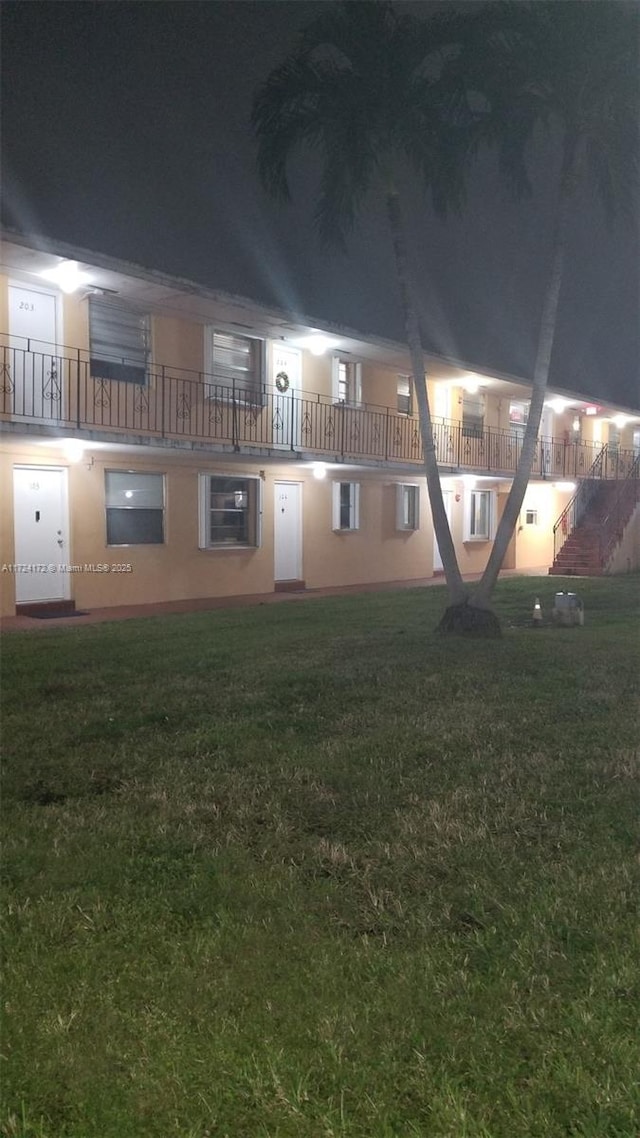 back house at night featuring a lawn