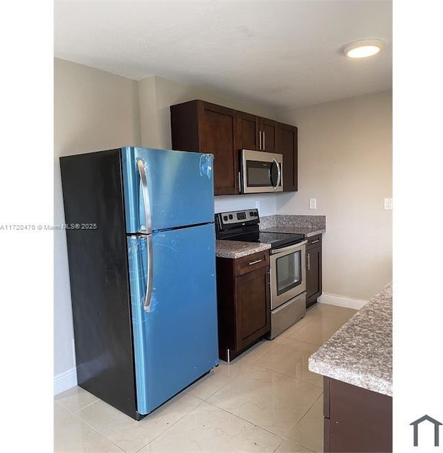 kitchen with dark brown cabinetry, light tile patterned floors, and stainless steel appliances