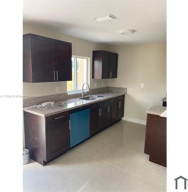 kitchen featuring light stone counters, dishwashing machine, dark brown cabinetry, sink, and light tile patterned flooring