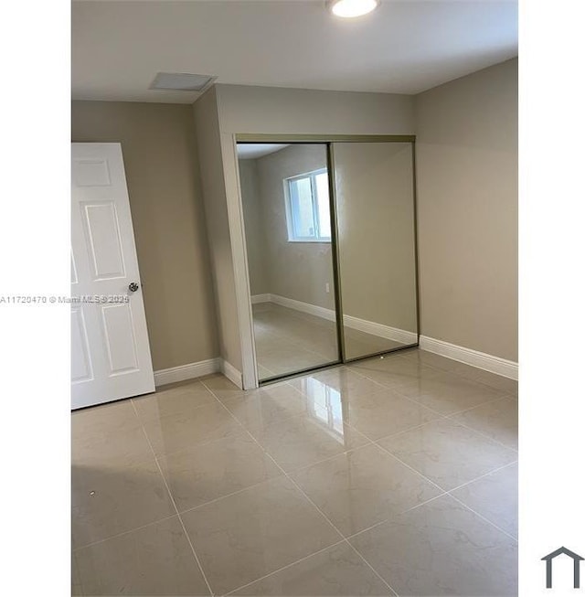 unfurnished bedroom featuring light tile patterned floors and a closet