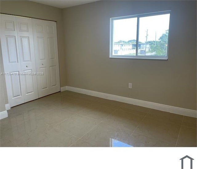 unfurnished bedroom with light tile patterned flooring and a closet