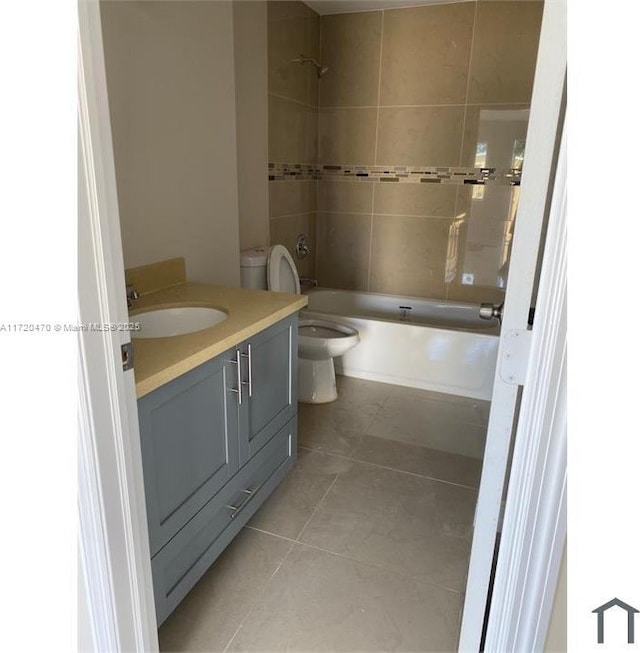 full bathroom with tile patterned floors, vanity, tiled shower / bath combo, and toilet