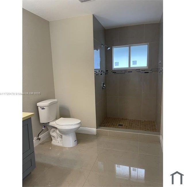 bathroom featuring tiled shower, vanity, toilet, and tile patterned flooring