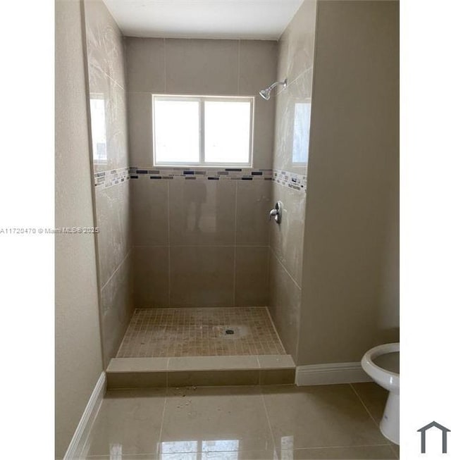 bathroom featuring tile patterned floors, a tile shower, and toilet