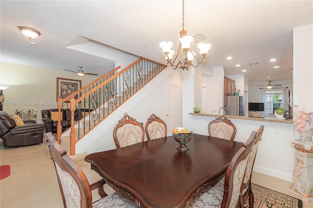 tiled dining space with ceiling fan with notable chandelier