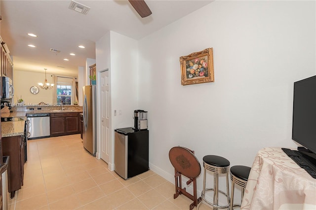 kitchen with light stone countertops, pendant lighting, stainless steel appliances, a breakfast bar area, and sink