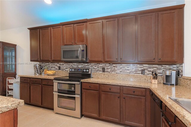 kitchen with stainless steel appliances, light stone counters, and tasteful backsplash