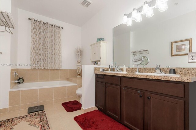 bathroom featuring a relaxing tiled tub, tile patterned flooring, vanity, and toilet