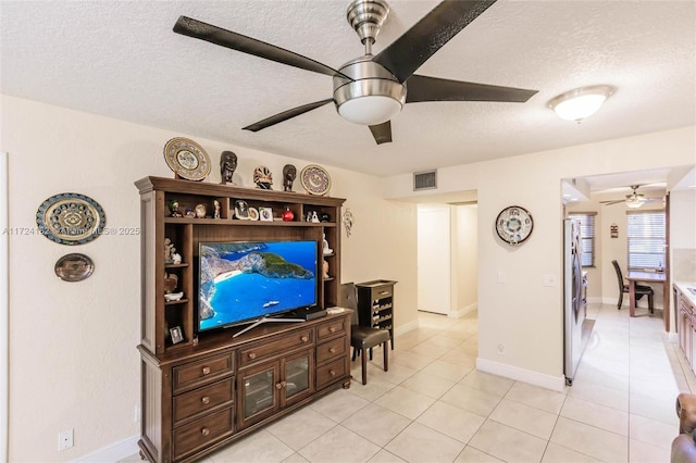living area featuring ceiling fan, light tile patterned floors, a textured ceiling, visible vents, and baseboards