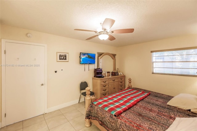 bedroom featuring ceiling fan, light tile patterned flooring, and a textured ceiling