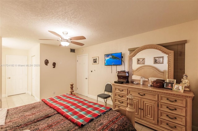 bedroom featuring ceiling fan, light tile patterned floors, and a textured ceiling