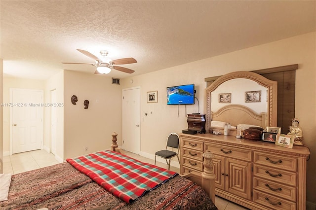 bedroom featuring visible vents, baseboards, light tile patterned floors, ceiling fan, and a textured ceiling