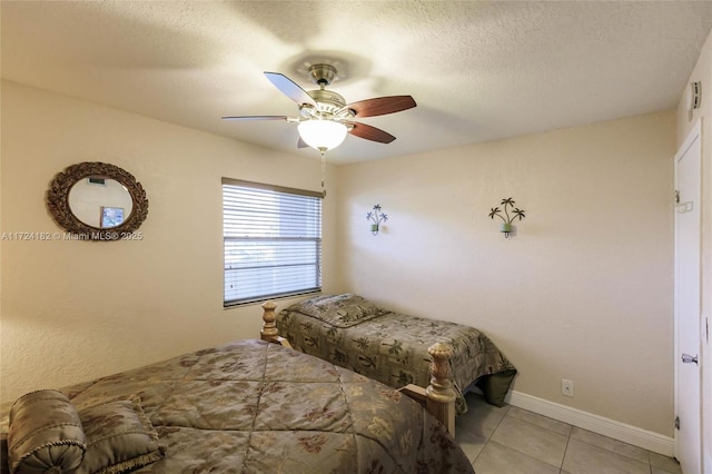 bedroom featuring ceiling fan, light tile patterned floors, and a textured ceiling