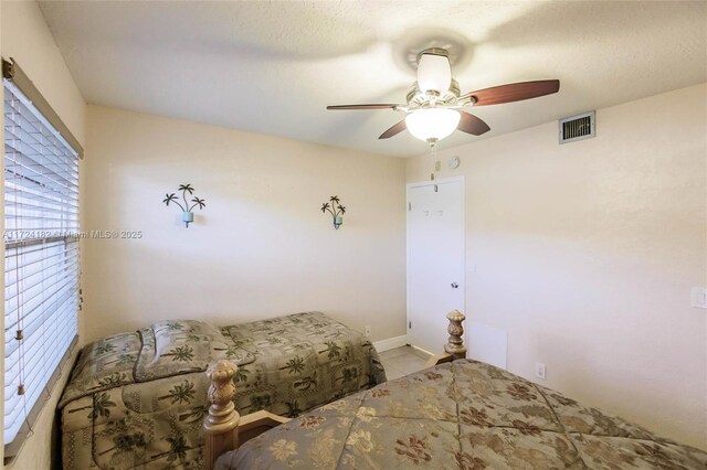 bedroom featuring visible vents, tile patterned floors, ceiling fan, and baseboards