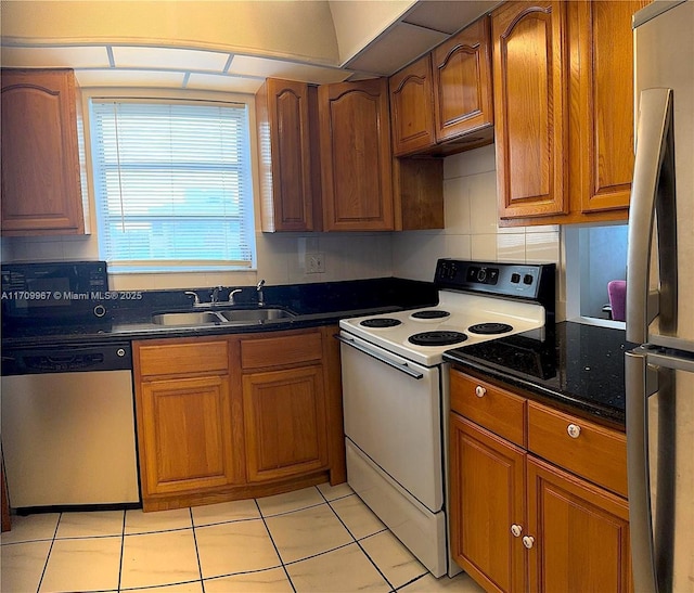 kitchen with light tile patterned flooring, stainless steel appliances, dark stone countertops, and sink