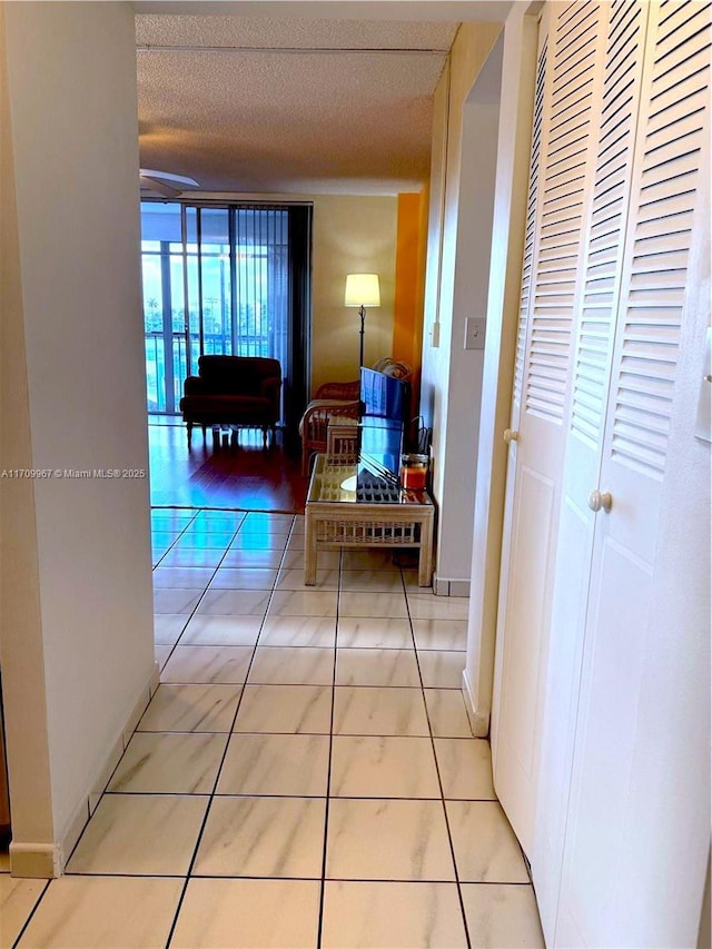 hall with light tile patterned floors and a textured ceiling