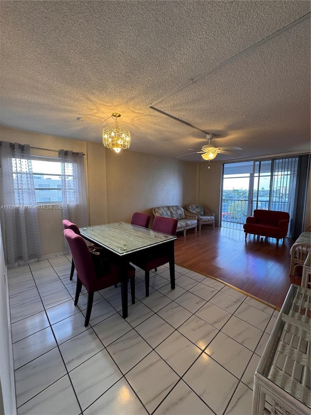 dining room with light tile patterned floors, ceiling fan with notable chandelier, a textured ceiling, and a wealth of natural light