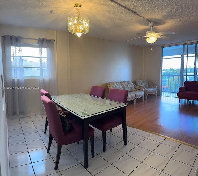 dining space with ceiling fan with notable chandelier, light tile patterned floors, and a textured ceiling