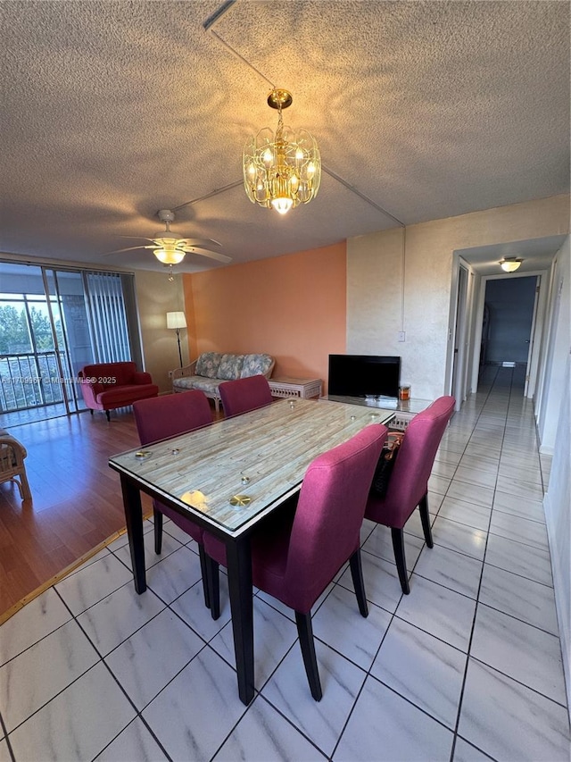 dining area with tile patterned flooring, ceiling fan with notable chandelier, floor to ceiling windows, and a textured ceiling