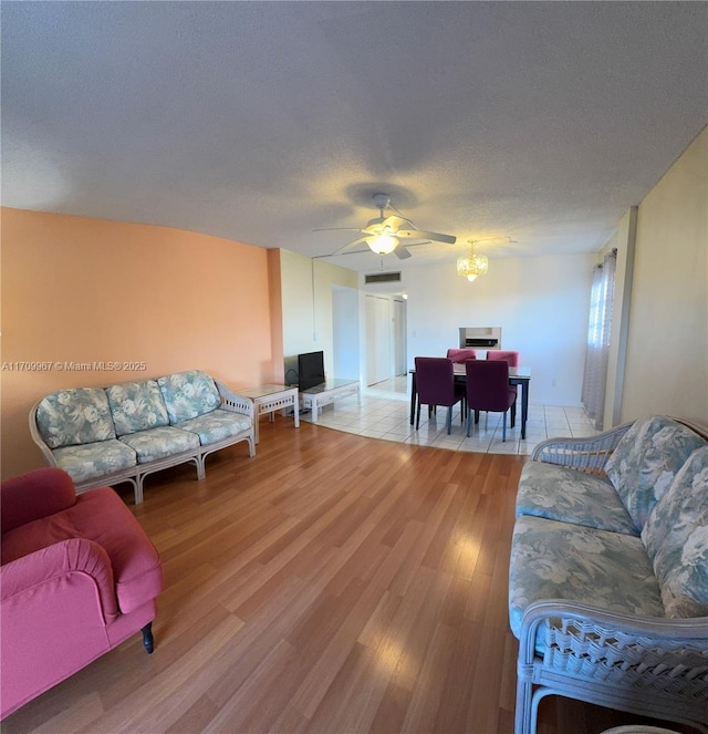 living room with ceiling fan, light hardwood / wood-style floors, and a textured ceiling