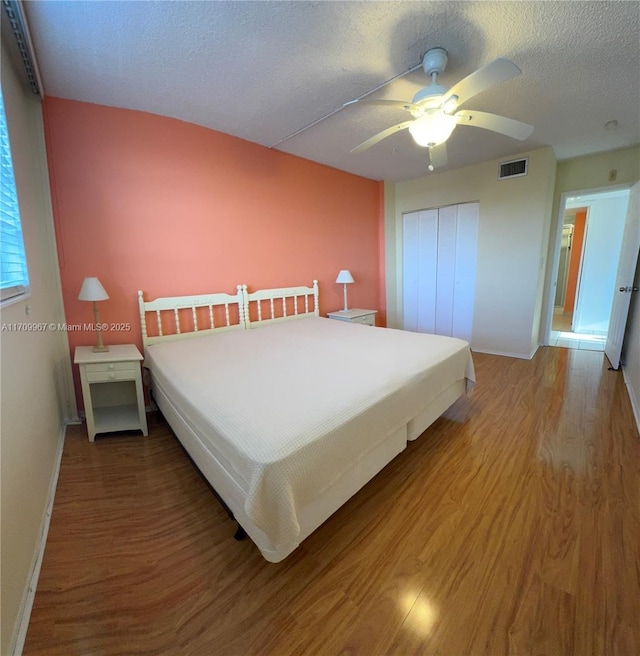 bedroom with hardwood / wood-style flooring, ceiling fan, and a textured ceiling