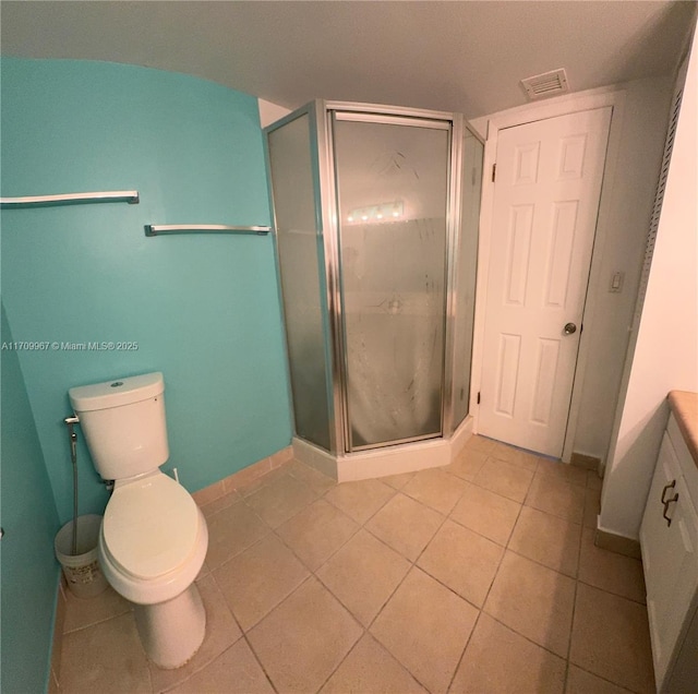 bathroom with tile patterned flooring, vanity, toilet, and a shower with door