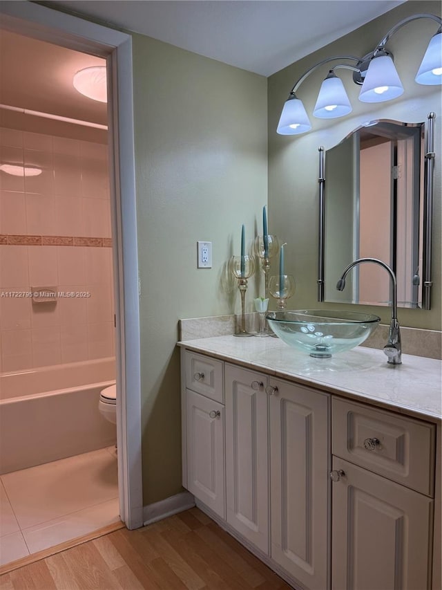 full bathroom with toilet, tiled shower / bath combo, vanity, and hardwood / wood-style floors