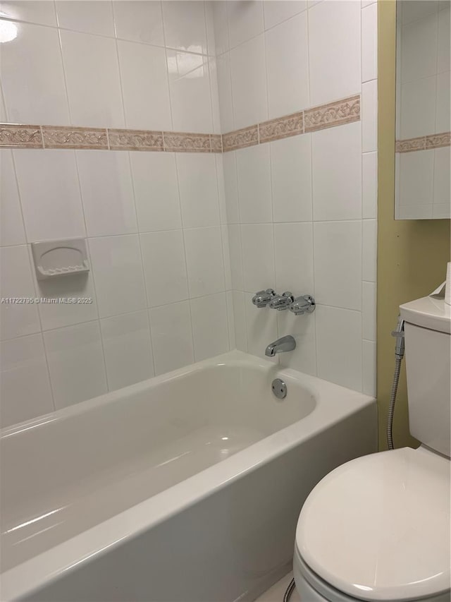 bathroom featuring toilet and tiled shower / bath