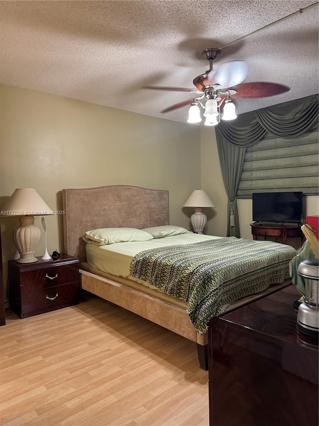 bedroom with a textured ceiling, ceiling fan, and light hardwood / wood-style floors