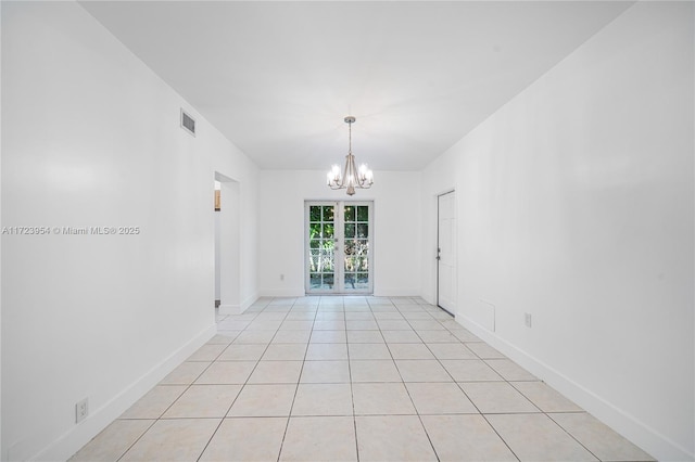 tiled spare room with a notable chandelier