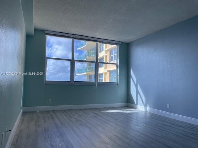 empty room featuring wood-type flooring and a textured ceiling