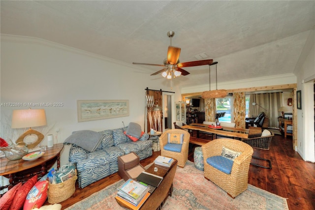 living room with ceiling fan, dark hardwood / wood-style floors, ornamental molding, and a barn door