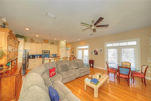 living room featuring ceiling fan, french doors, and light wood-type flooring