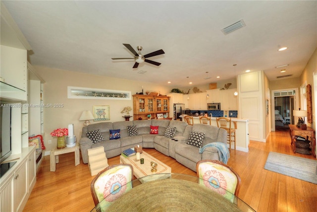 living room featuring ceiling fan and light hardwood / wood-style floors