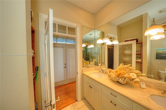 bathroom with toilet, vanity, and tile patterned flooring