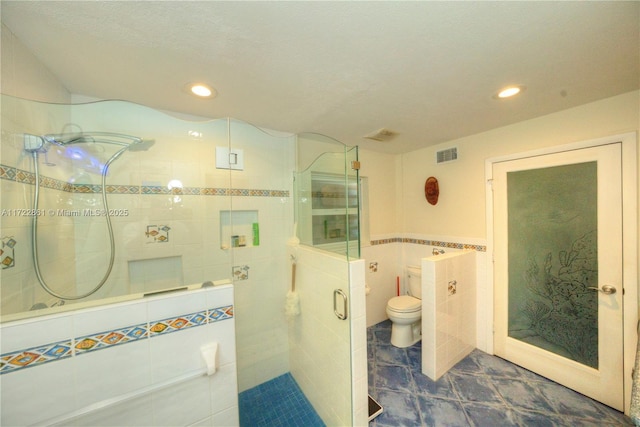 bathroom featuring toilet, a textured ceiling, tile walls, and walk in shower