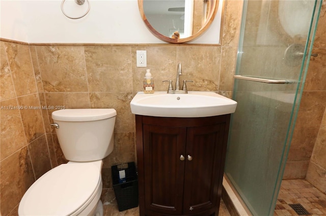 bathroom featuring walk in shower, vanity, toilet, and tile walls