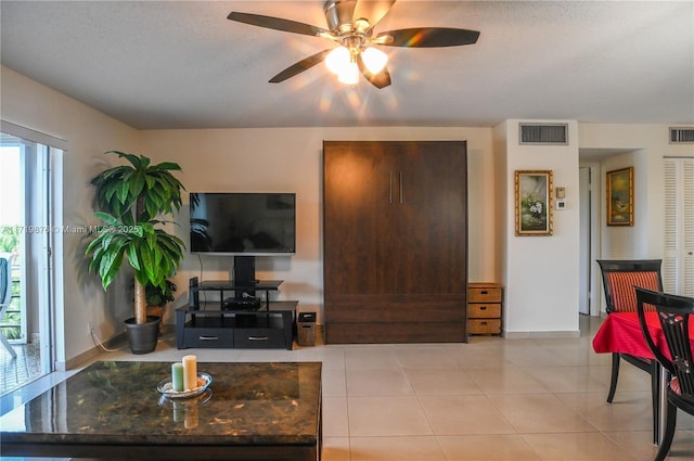 tiled living room with ceiling fan and a textured ceiling