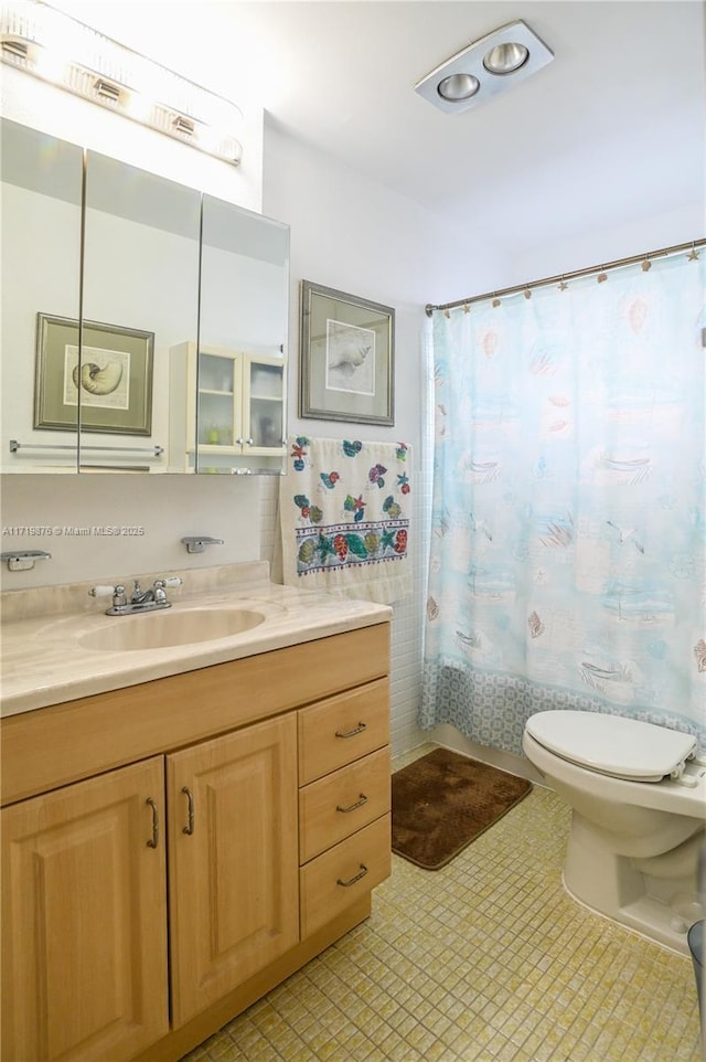 full bathroom with vanity, shower / bath combination with curtain, and toilet