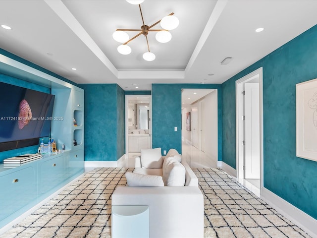 living room featuring built in features, a raised ceiling, and a chandelier