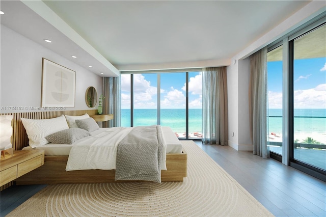 bedroom with a water view, expansive windows, and access to exterior