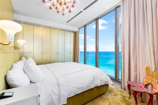 bedroom featuring multiple windows, access to exterior, expansive windows, and a water view