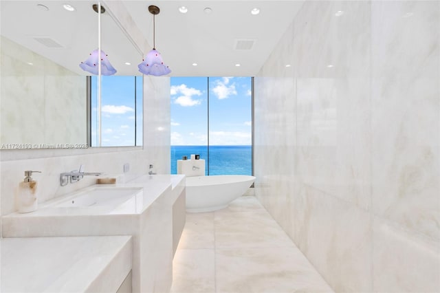 bathroom featuring tile walls, a bathtub, plenty of natural light, and a water view