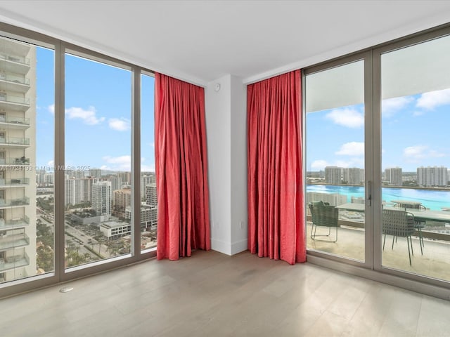 empty room featuring floor to ceiling windows, hardwood / wood-style floors, and a water view