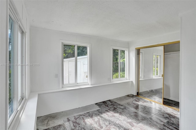 unfurnished room with a healthy amount of sunlight and a textured ceiling