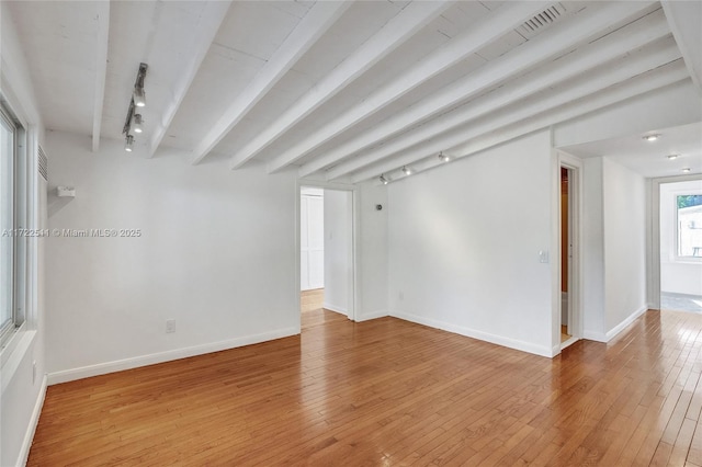 empty room with hardwood / wood-style floors, beamed ceiling, and track lighting