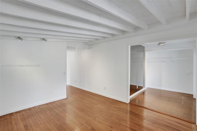 empty room with hardwood / wood-style floors and beam ceiling