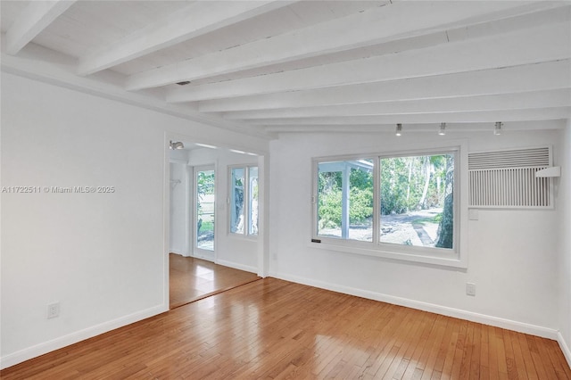 empty room with hardwood / wood-style floors and beam ceiling