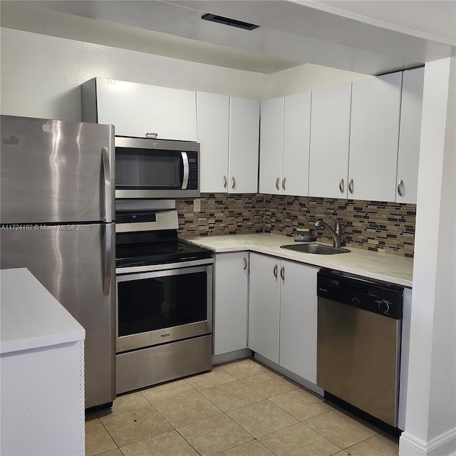 kitchen with appliances with stainless steel finishes, backsplash, a sink, and light countertops